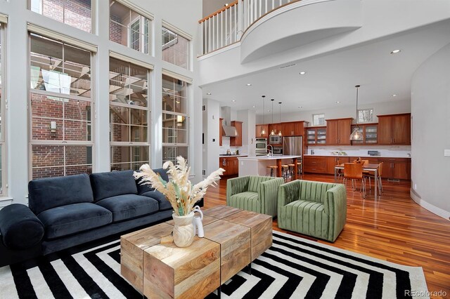 8044 E 24th Ave, Denver, CO 80238 - living area featuring light wood-style flooring, healthy amount of natural light, recessed lighting, a towering ceiling, and baseboards