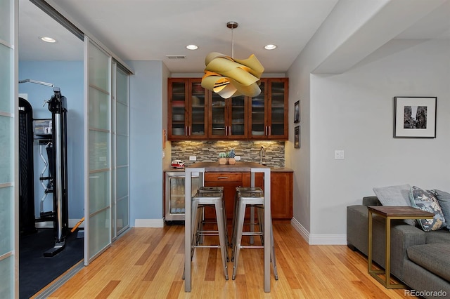 8044 E 24th Ave, Denver, CO 80238 - bar featuring wine cooler, backsplash, light wood-style flooring, baseboards, and decorative light fixtures