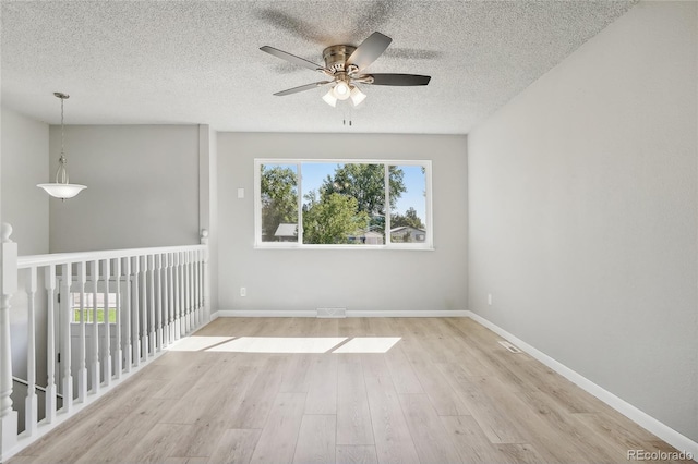 unfurnished room with light wood-type flooring, a textured ceiling, and ceiling fan