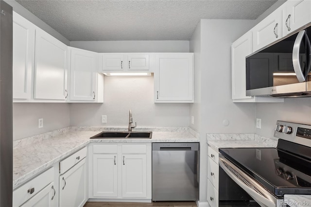 kitchen with white cabinetry, a textured ceiling, appliances with stainless steel finishes, and sink