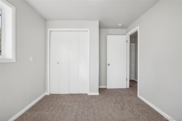 unfurnished bedroom with light carpet and a closet