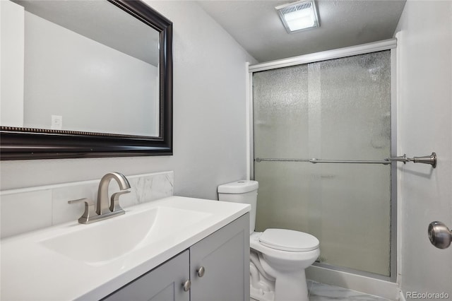 bathroom with a shower with door, vanity, and toilet