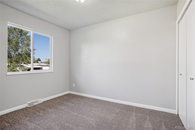 empty room with a textured ceiling and carpet flooring