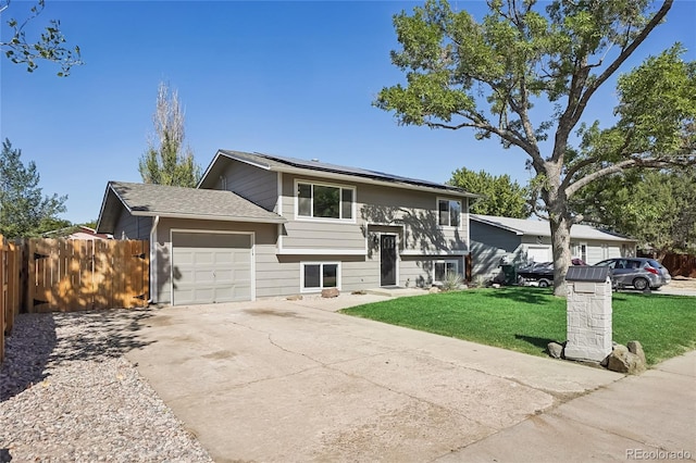 raised ranch featuring a garage and a front yard