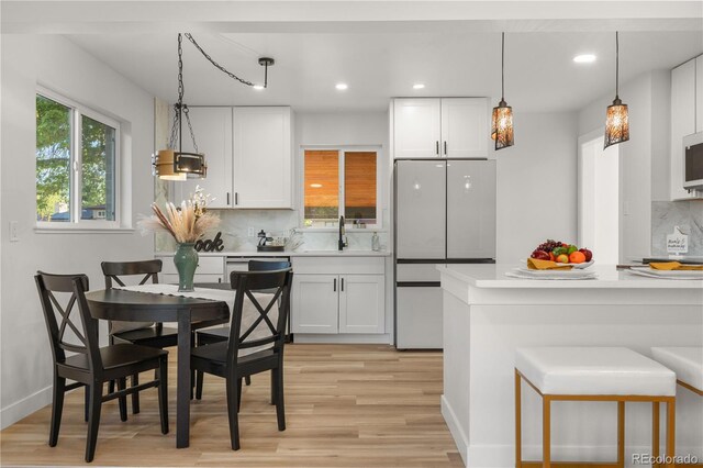 3541 Eudora St, Denver, CO 80207 - kitchen featuring freestanding refrigerator, light wood-style floors, backsplash, white cabinetry, and light countertops