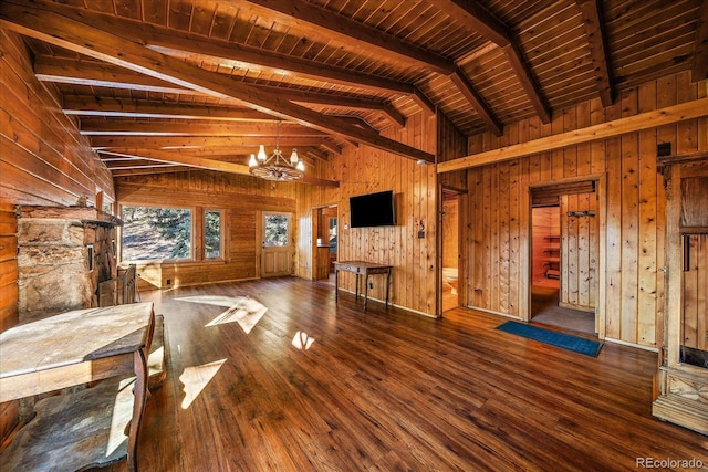 unfurnished living room with vaulted ceiling with beams, wooden walls, a notable chandelier, wood finished floors, and wood ceiling