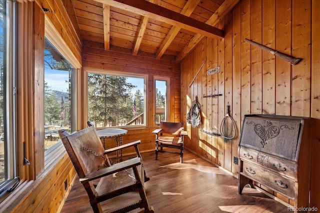 living area featuring lofted ceiling with beams, wood walls, wooden ceiling, and wood finished floors