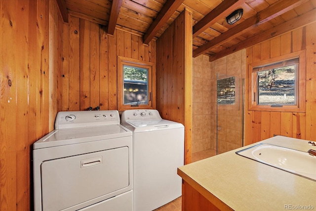 laundry area with wooden ceiling, washing machine and dryer, a sink, wood walls, and laundry area