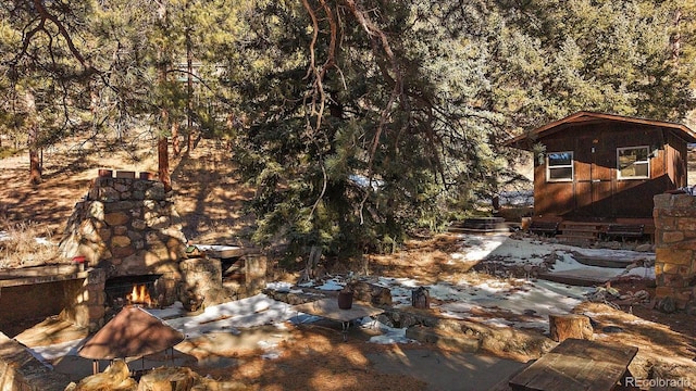 view of yard with an outdoor stone fireplace and a forest view