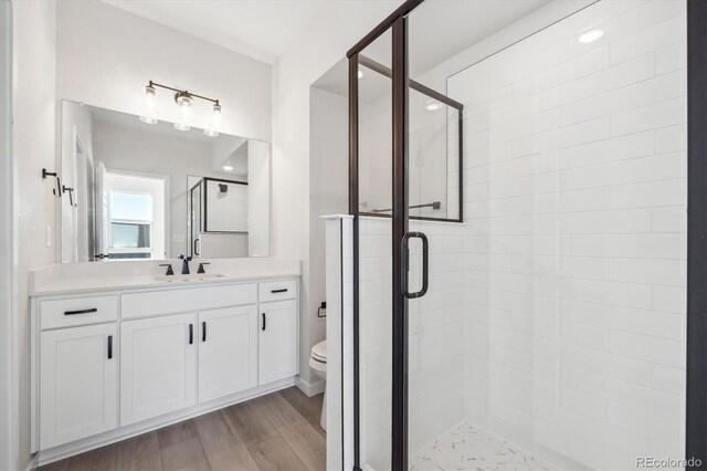 bathroom with vanity, toilet, a shower with shower door, and wood-type flooring