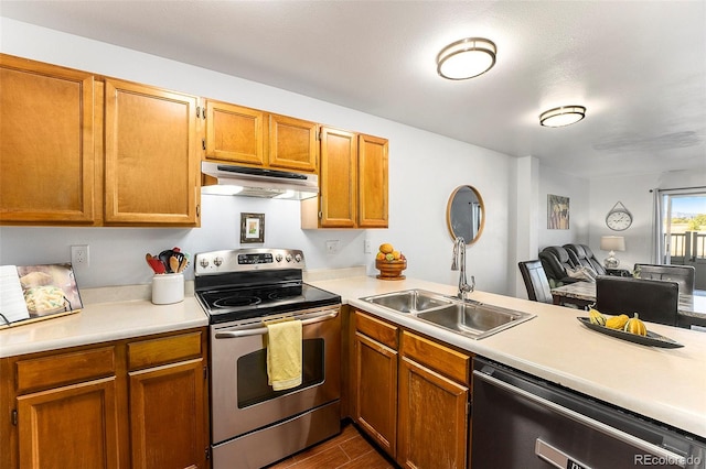 kitchen with dark wood-type flooring, kitchen peninsula, stainless steel appliances, a textured ceiling, and sink