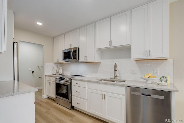 kitchen featuring a sink, white cabinets, appliances with stainless steel finishes, and light stone counters
