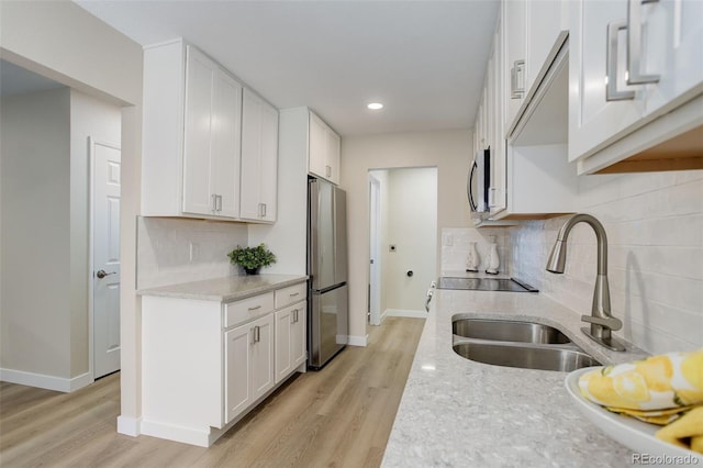 kitchen featuring a sink, white cabinets, appliances with stainless steel finishes, and light stone counters