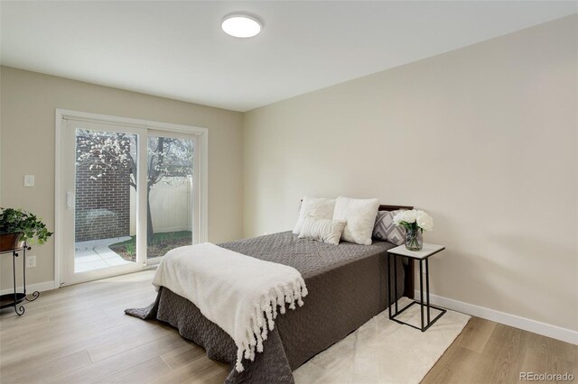 bedroom featuring access to exterior, light wood finished floors, and baseboards