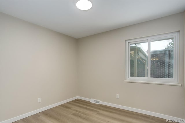 spare room with visible vents, baseboards, and light wood finished floors