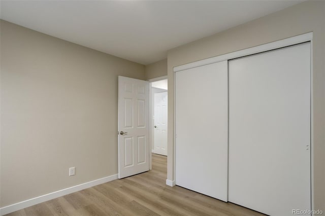 unfurnished bedroom with a closet, baseboards, and light wood finished floors