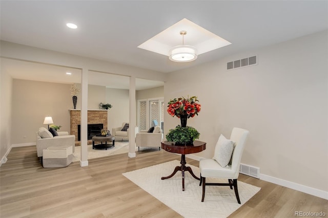 sitting room featuring visible vents, baseboards, light wood-type flooring, and a fireplace
