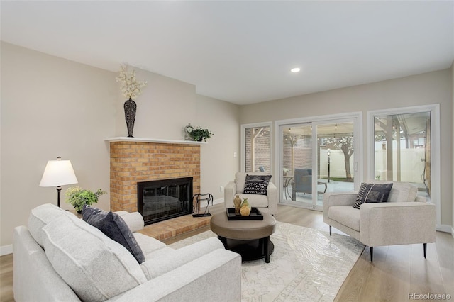 living room with light wood finished floors, baseboards, a brick fireplace, and recessed lighting
