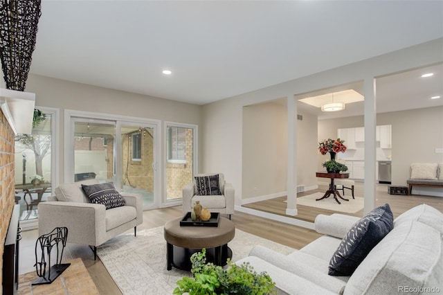 living room featuring light wood-style floors, baseboards, visible vents, and recessed lighting