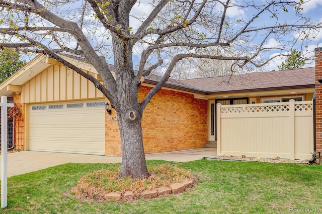 ranch-style home with a garage, fence, concrete driveway, brick siding, and a front lawn