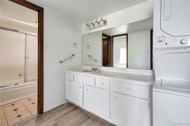 2525 S Dayton Way Unit 1510, Denver, CO 80231 - full bathroom with stacked washer / dryer, vanity, combined bath / shower with glass door, and wood finished floors