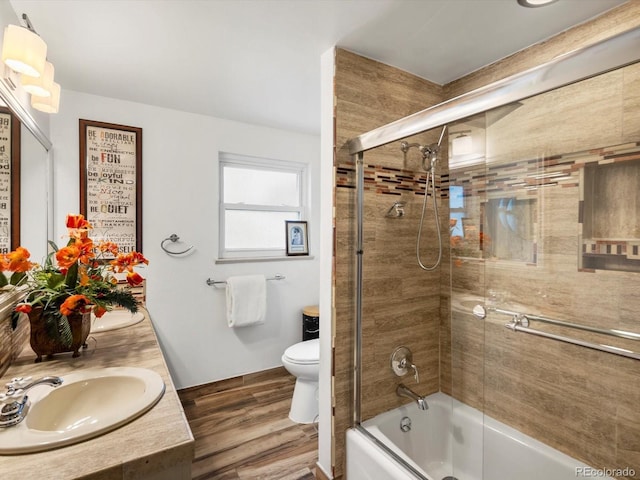 5845 W Portland Dr, Littleton, CO 80128 - bathroom featuring wood finished floors, toilet, combined bath / shower with glass door, and double vanity