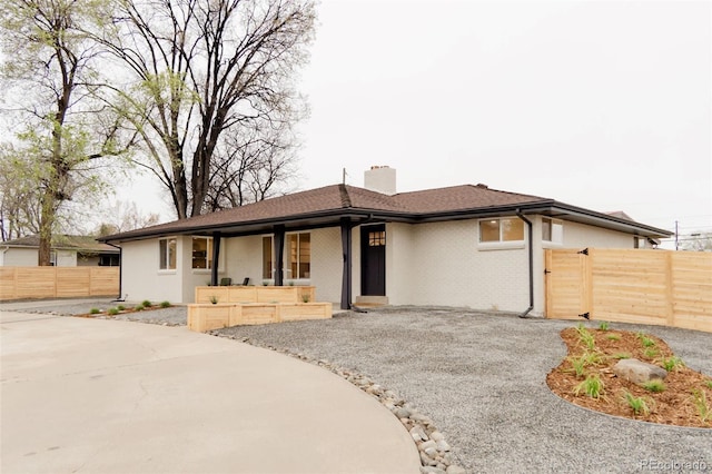 4395 Newland St, Wheat Ridge, CO 80033 - view of front facade with a chimney, a porch, and asphalt driveway