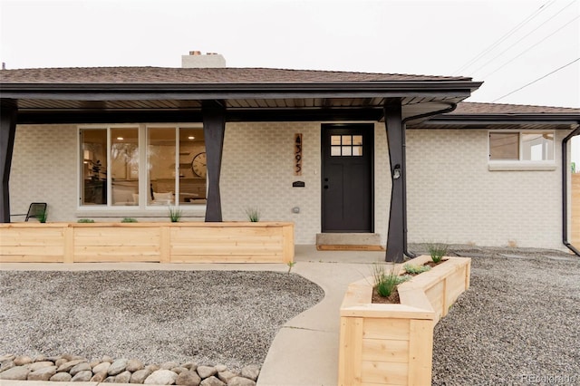 4395 Newland St, Wheat Ridge, CO 80033 - property entrance featuring a shingled roof, a chimney, covered porch, and brick siding