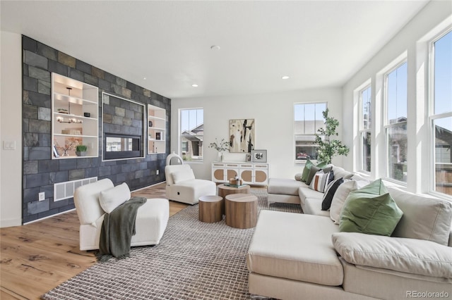 living area with baseboards, built in features, wood finished floors, and visible vents