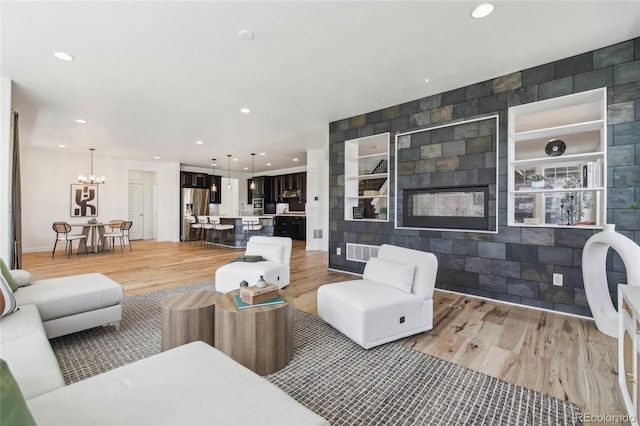 living room featuring light wood finished floors, an inviting chandelier, and recessed lighting