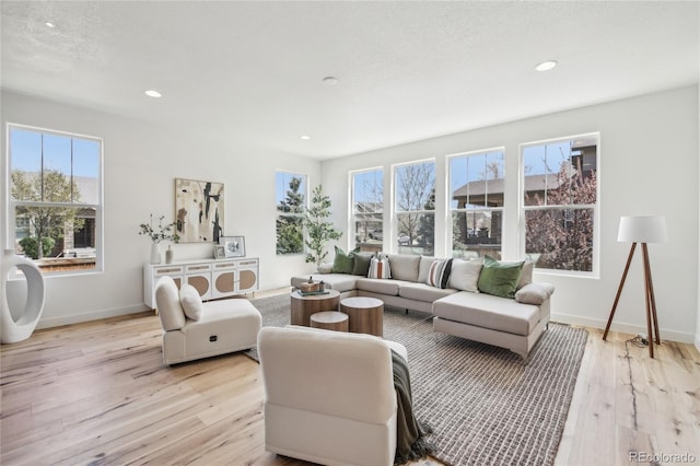 living room featuring baseboards, recessed lighting, and light wood-style floors