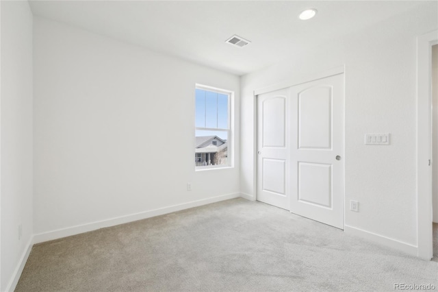 unfurnished bedroom with a closet, carpet floors, visible vents, and baseboards
