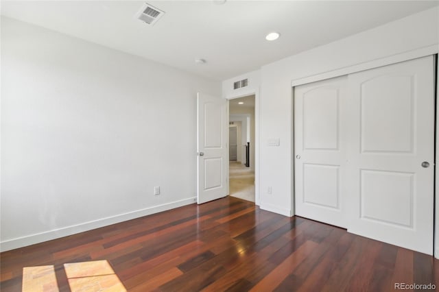 unfurnished bedroom featuring wood finished floors, a closet, baseboards, visible vents, and recessed lighting