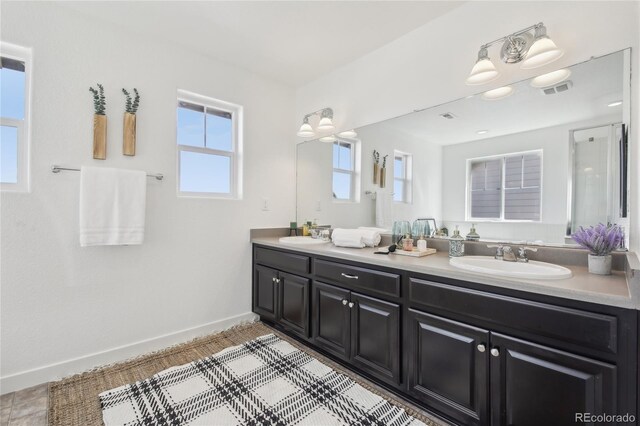bathroom with baseboards, visible vents, a sink, and double vanity