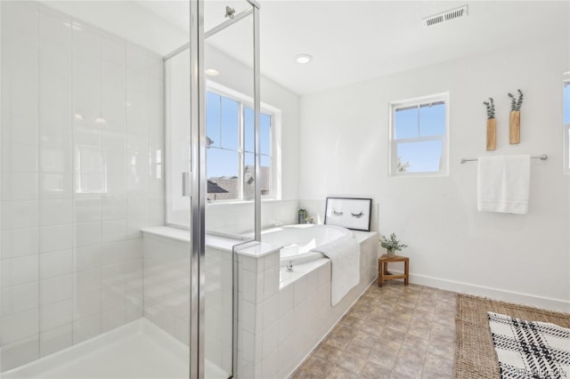 bathroom with a shower stall, a garden tub, visible vents, and baseboards