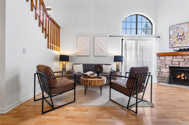 942 S Walden St Unit 204, Aurora, CO 80017 - living area with wood finished floors, stairway, a high ceiling, baseboards, and a stone fireplace