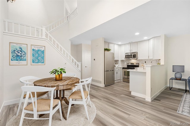 2017 N Fork Dr, Lafayette, CO 80026 - kitchen with appliances with stainless steel finishes, light wood-type flooring, tasteful backsplash, light countertops, and a peninsula