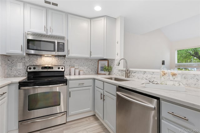 2017 N Fork Dr, Lafayette, CO 80026 - kitchen featuring appliances with stainless steel finishes, a sink, light stone countertops, decorative backsplash, and light wood finished floors