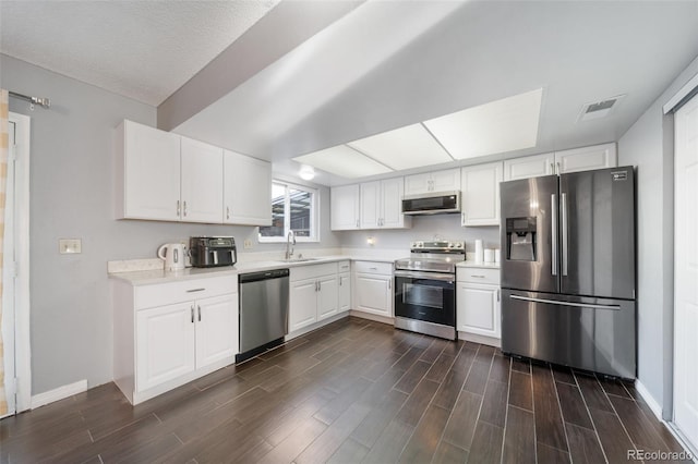 kitchen with white cabinets, stainless steel appliances, dark hardwood / wood-style flooring, sink, and a textured ceiling