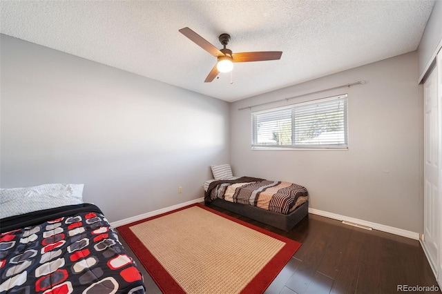 bedroom with dark hardwood / wood-style flooring, ceiling fan, and a textured ceiling