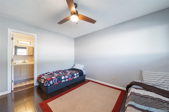 bedroom with a textured ceiling, dark hardwood / wood-style flooring, ensuite bath, sink, and ceiling fan