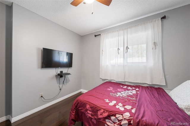 bedroom with ceiling fan, dark hardwood / wood-style floors, and a textured ceiling