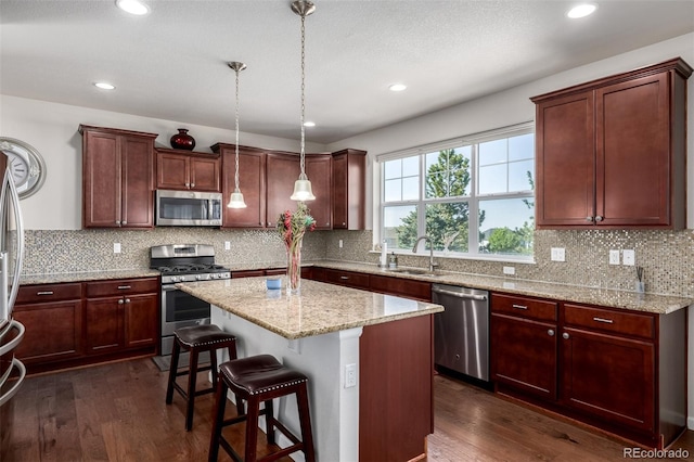 27029 E Irish Pl, Aurora, CO 80016 - kitchen featuring stainless steel appliances, dark wood-type flooring, a kitchen island, a breakfast bar, and recessed lighting