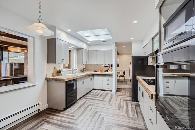 kitchen with a baseboard heating unit, white cabinets, hanging light fixtures, black appliances, and light parquet flooring