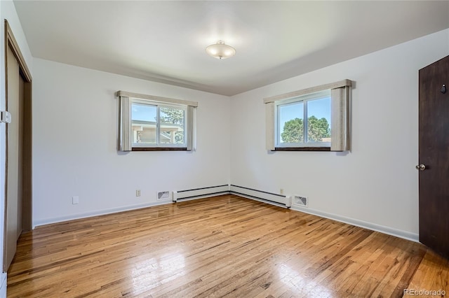 unfurnished bedroom with a baseboard heating unit, light hardwood / wood-style flooring, and multiple windows