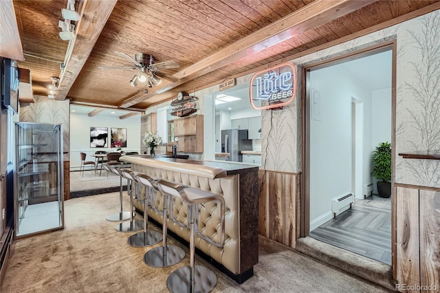 kitchen with stainless steel refrigerator with ice dispenser, wood ceiling, baseboard heating, and beamed ceiling