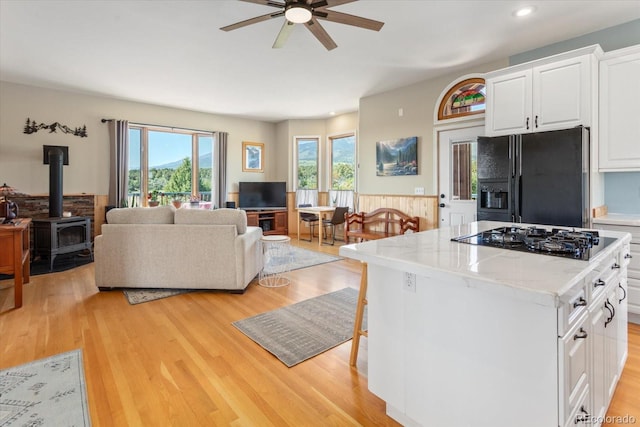 10 N Price Park, Cotopaxi, CO 81223 - kitchen with black appliances, a wood stove, ceiling fan, open floor plan, and light wood-style flooring