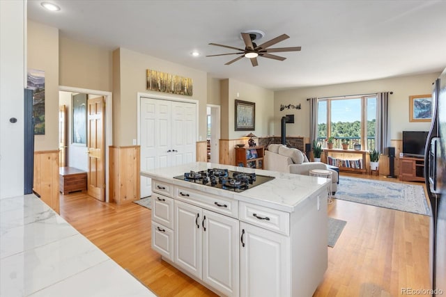 10 N Price Park, Cotopaxi, CO 81223 - kitchen featuring black gas stovetop, a wood stove, a ceiling fan, white cabinets, and open floor plan