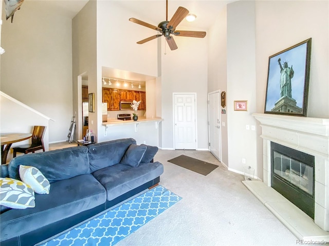 carpeted living room with a towering ceiling and ceiling fan