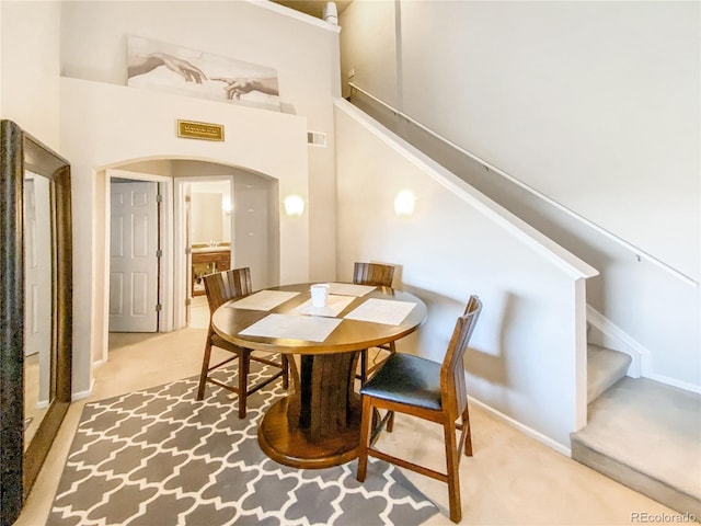 dining area featuring carpet and a towering ceiling